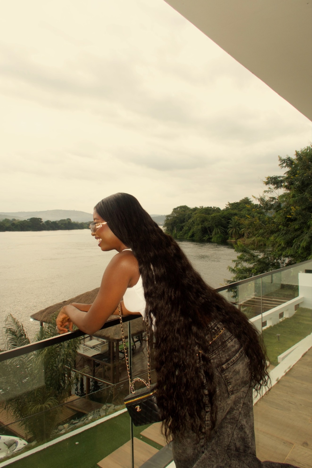 Model with long deep wave hair on a balcony over the lake